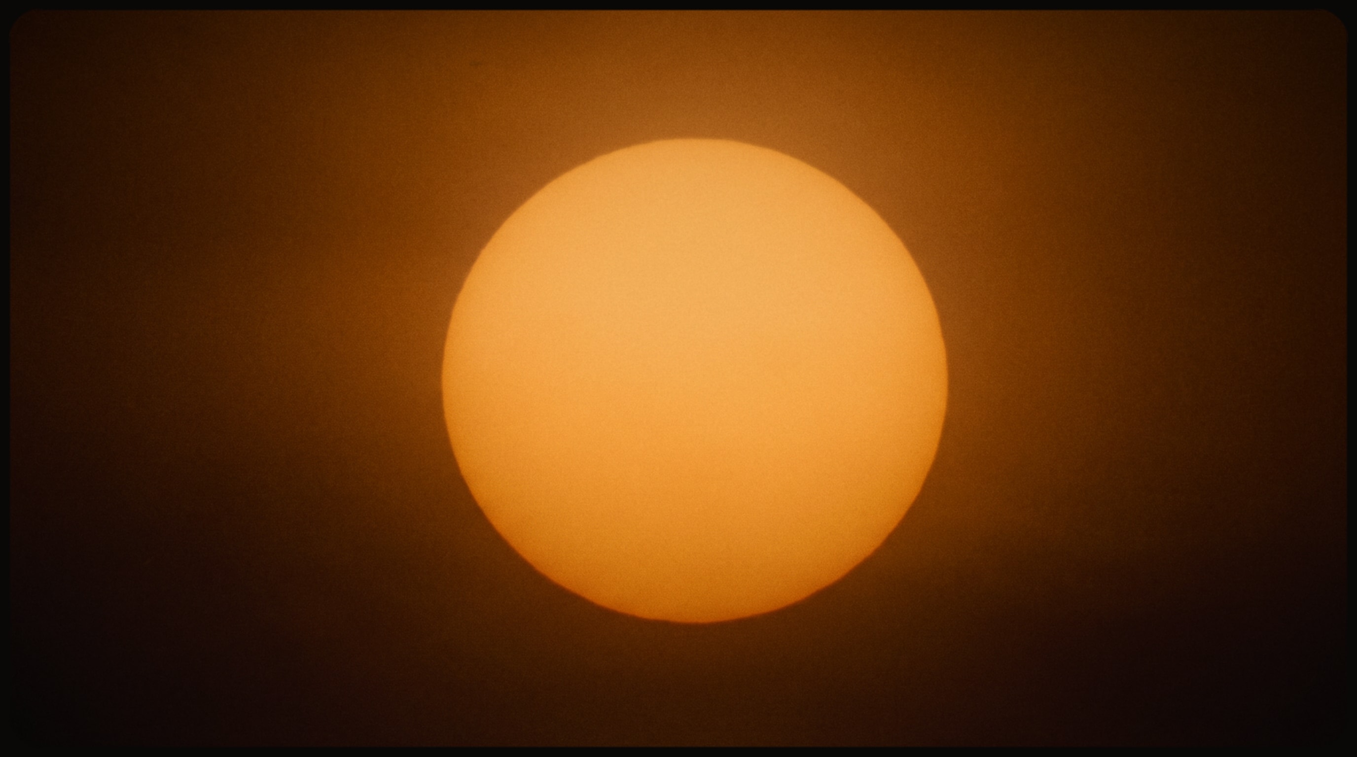 The sun, a clear disc of gold light in a dark amber sky